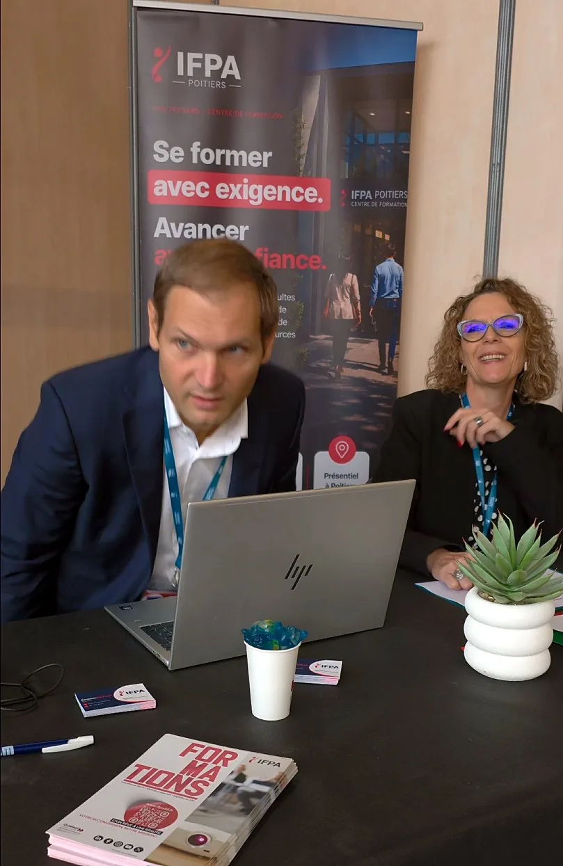 Stand de l'IFPA Poitiers au salon 24 Heures pour l'Emploi et la Formation : deux membres de l'équipe derrière une table avec un ordinateur portable et des brochures « Formations », devant le kakémono « Se former avec exigence. Avancer avec confiance. »